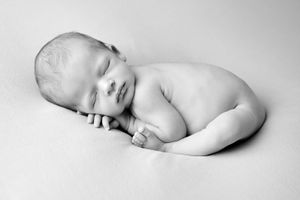 Black and white artistic portrait of sleeping newborn in fetal position.
