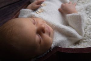 Sleeping newborn baby wrapped in soft white blanket.