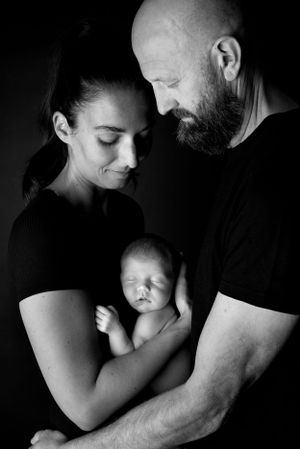 Artistic black and white family portrait with parents holding their newborn baby.
