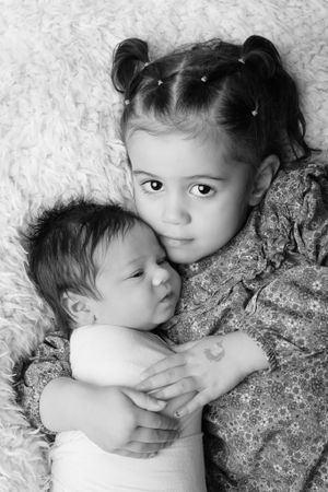 Black and white portrait of siblings on white textured background.