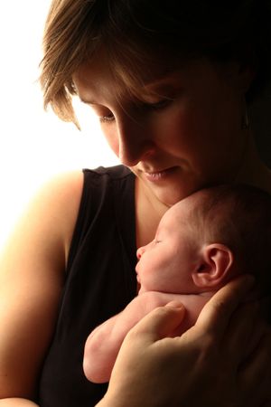 Moment intime entre un nouveau-né et sa maman capturé dans une lumière chaleureuse.