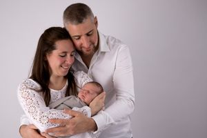 Famille de trois partageant un moment tendre ensemble contre un fond lumineux en studio.