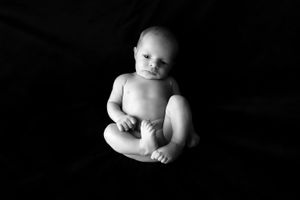 Portrait en noir et blanc d’un bébé couché contre un fond sombre.
