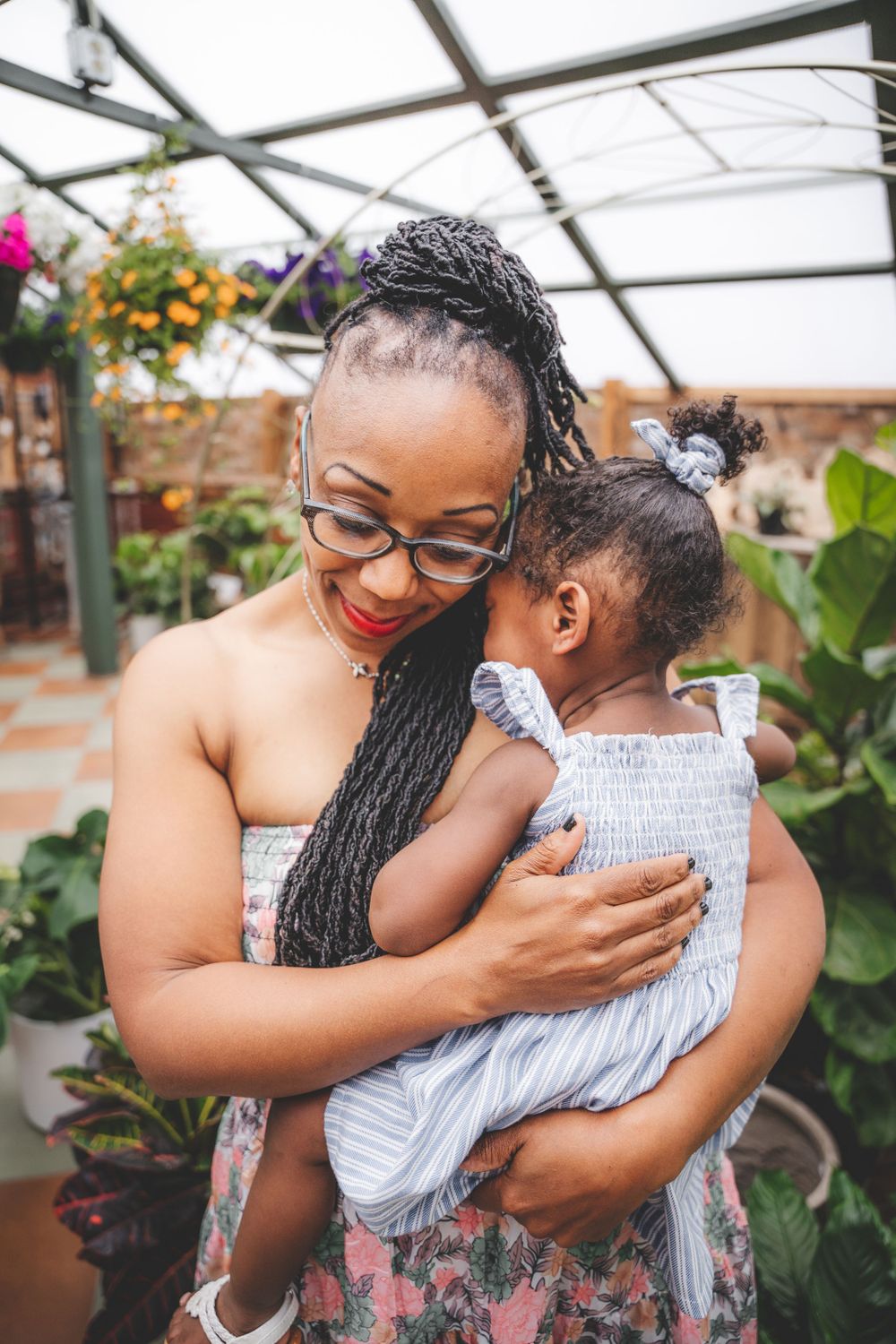 Tender embrace captured in a greenhouse setting with lush plants and natural lighting.