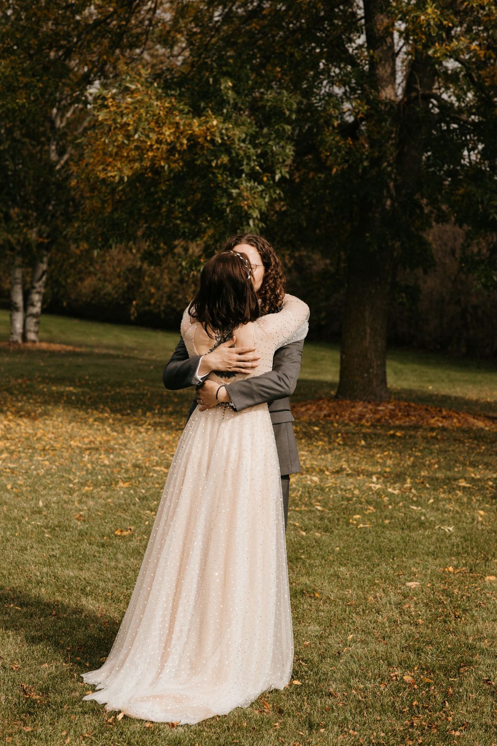 Bride and groom share emotional embrace in autumn garden during wedding first look.