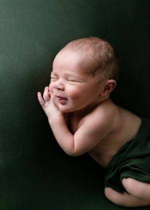 Orlando Newborn Photography, 21 Moments Photography, newborn boy smiling in his sleep laying on green backdrop