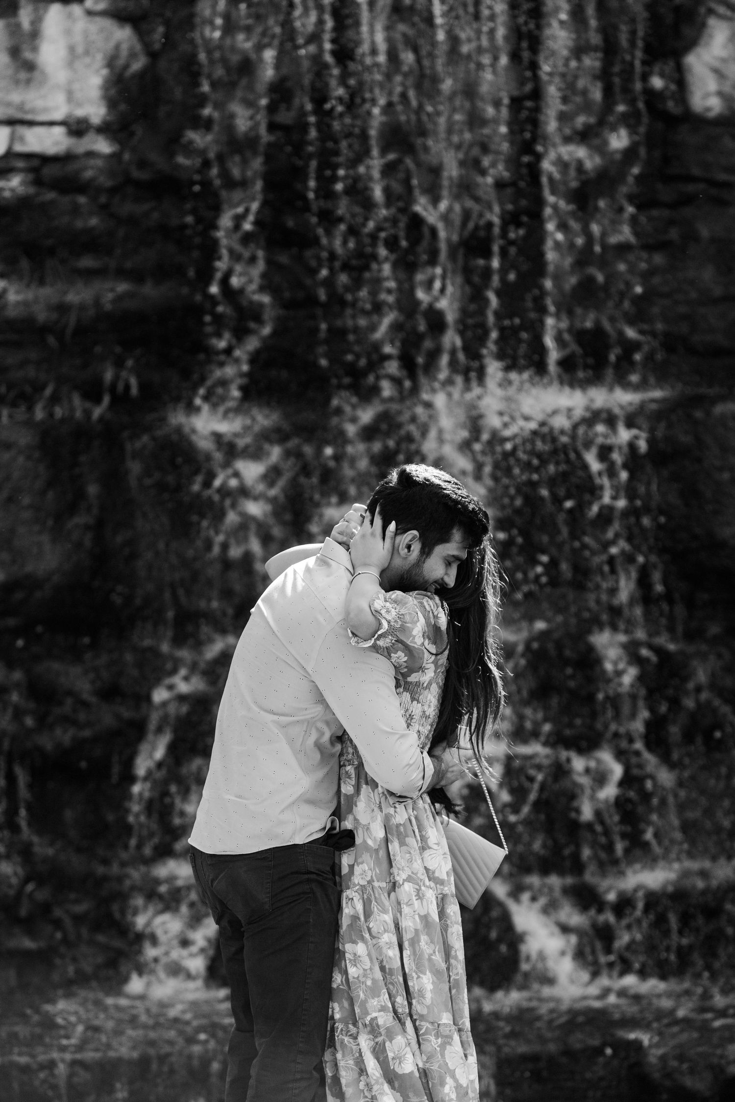 black and white couple hugging in front of waterfall