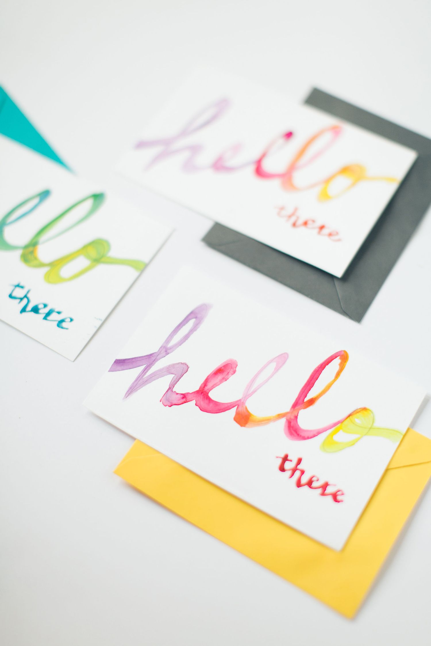Colorful watercolor hello cards with handwritten lettering in bright rainbow hues.
