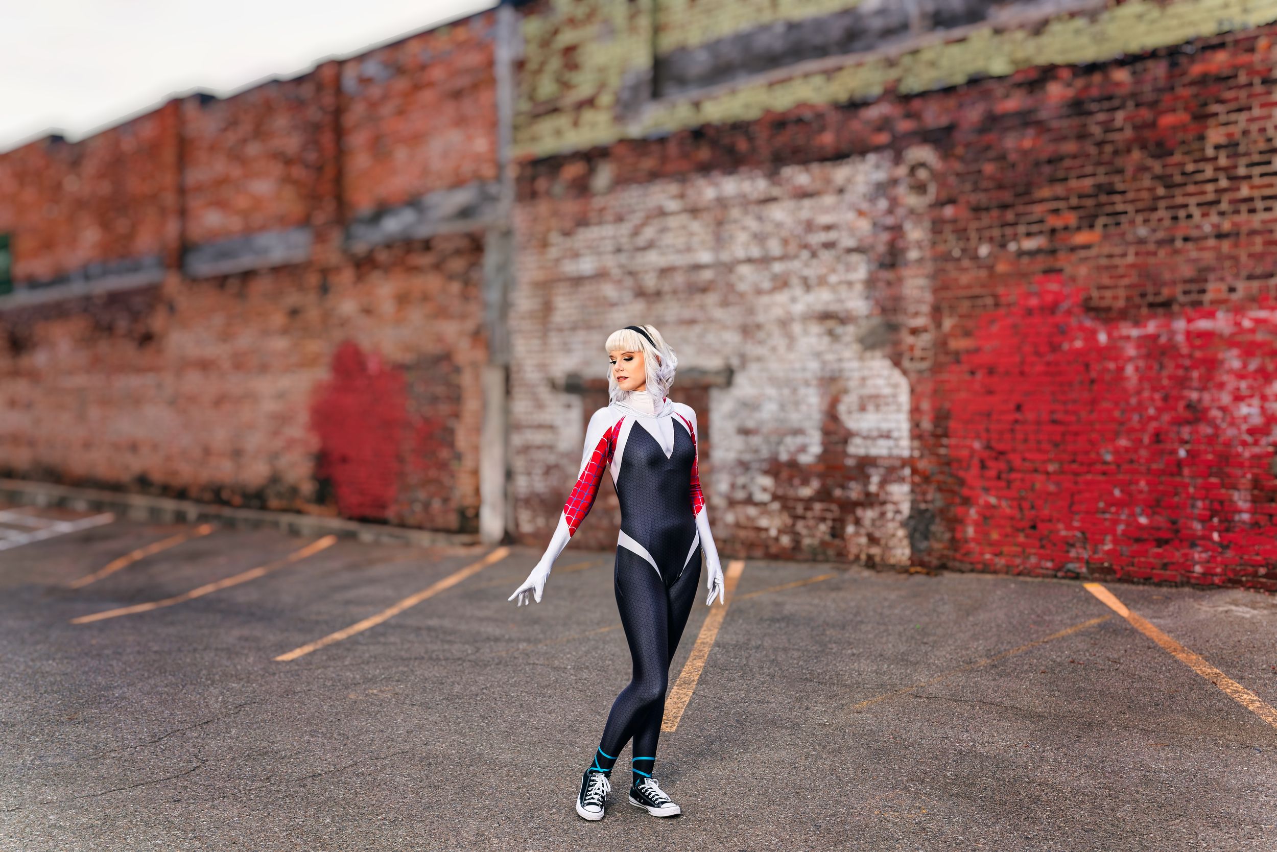 Dancer strikes graceful pose against weathered red brick wall background.