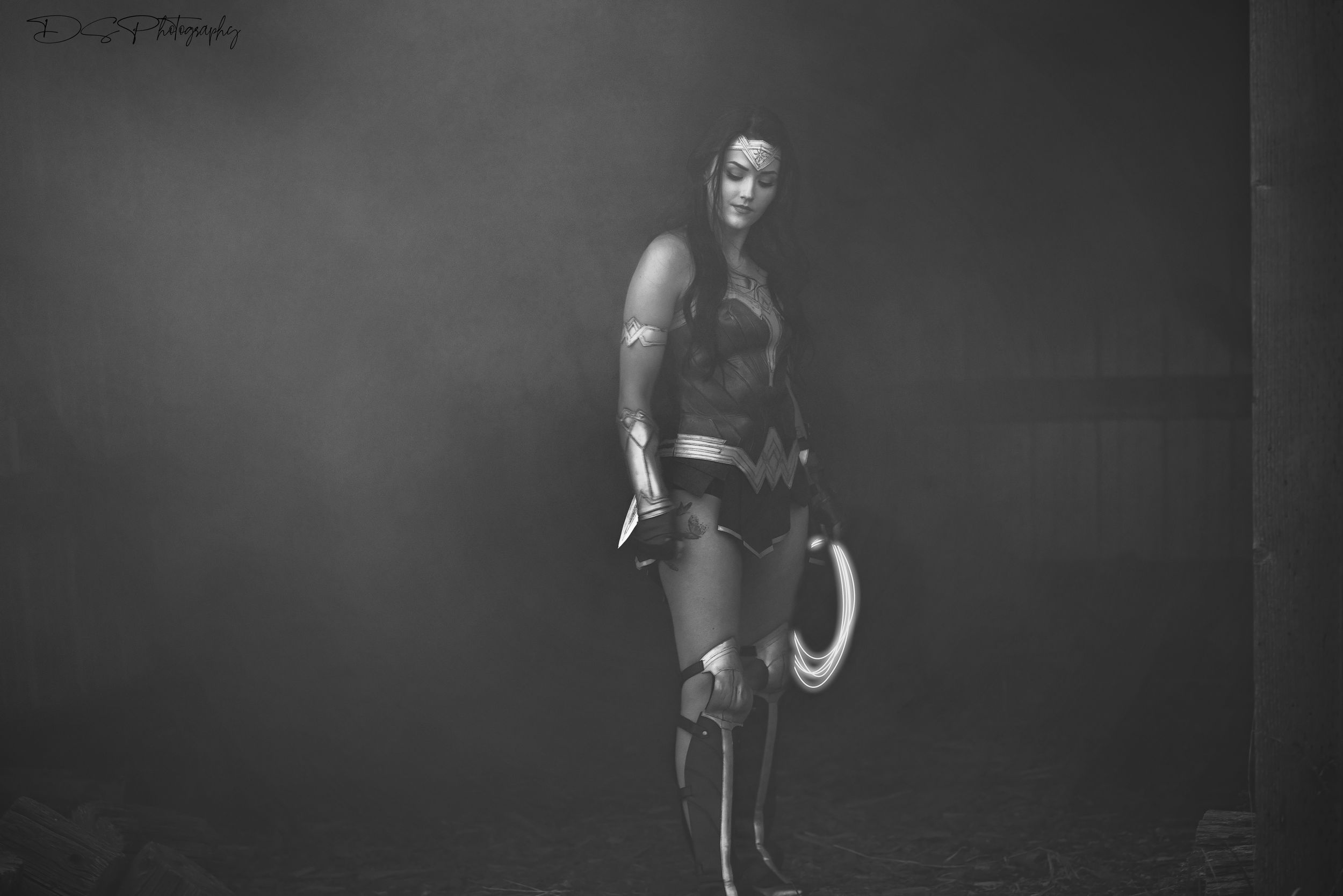 Dramatic black and white portrait of Wonder Woman with shield in dark setting.