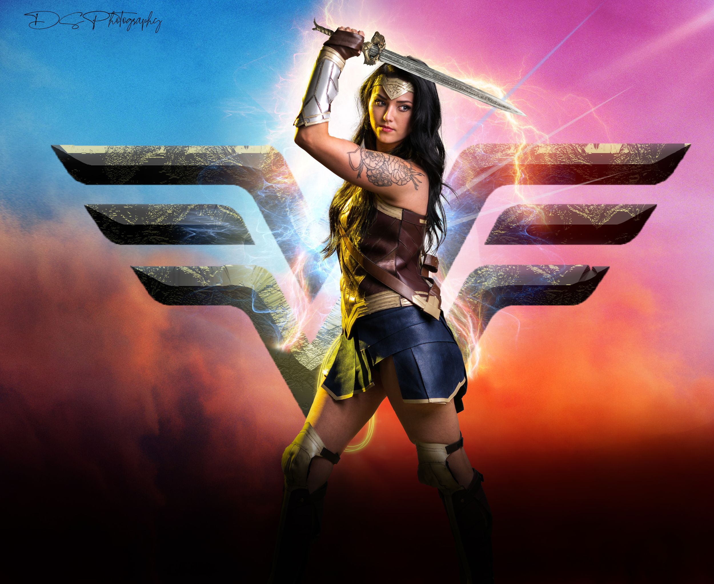 Wonder Woman poses heroically against sunset sky with iconic winged logo.