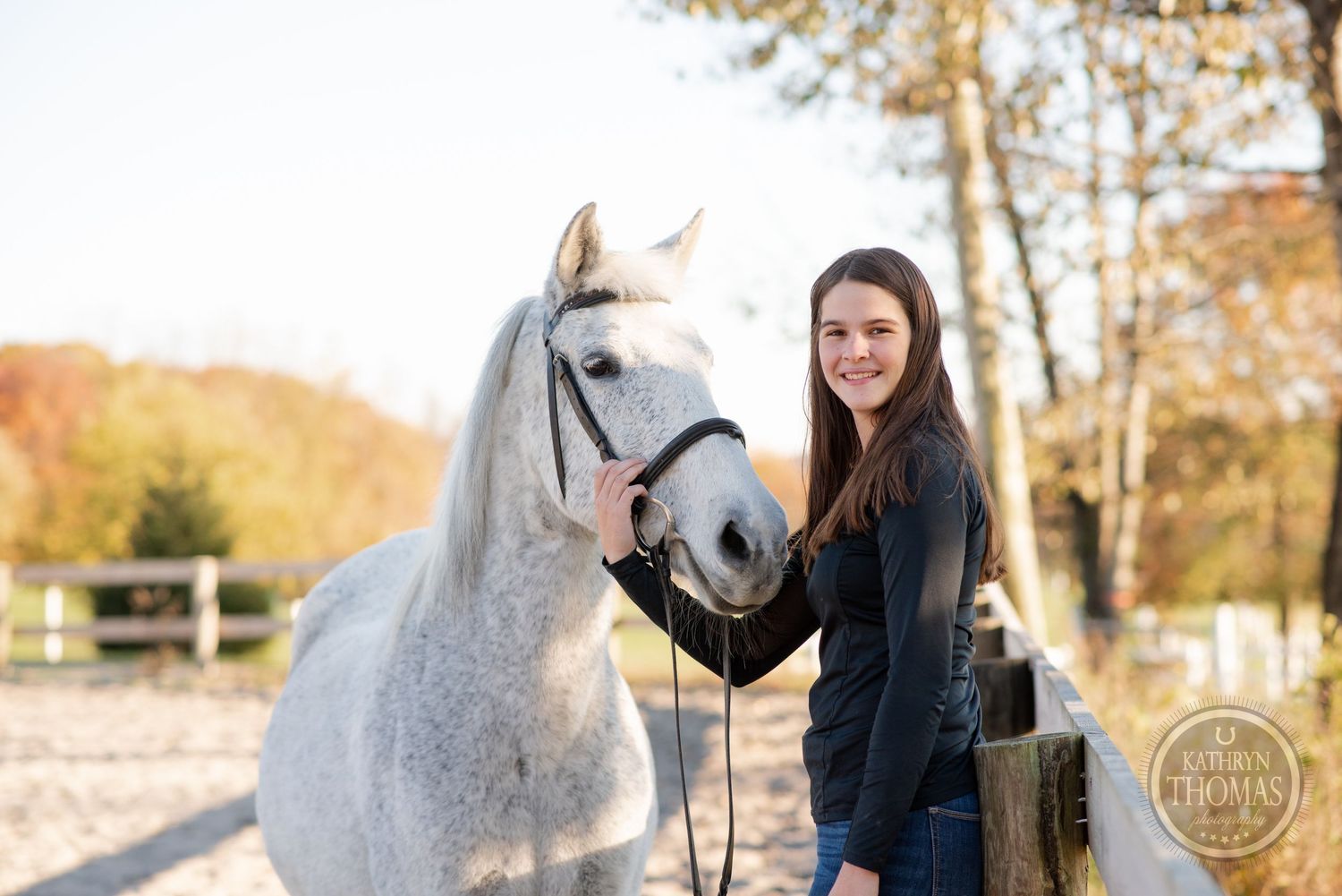 A friendly white horse and companion share a moment together by a wooden fence post.