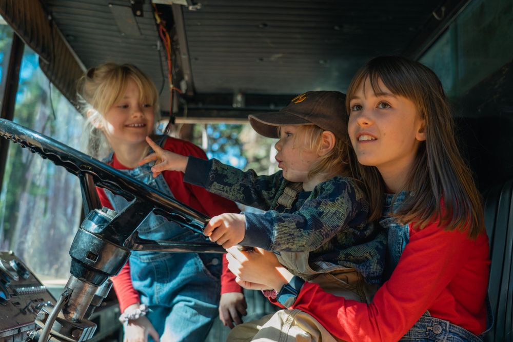 People sitting in vintage vehicle interior with steering wheel and dashboard visible.