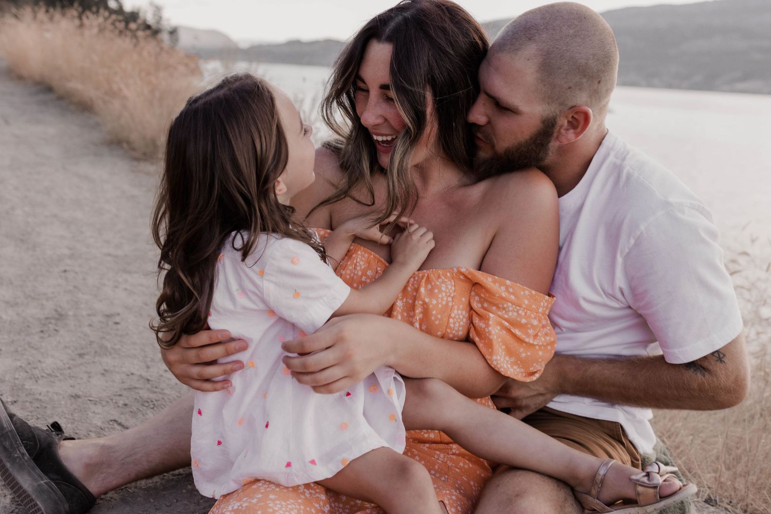 Family sharing an intimate moment together outdoors at sunset.