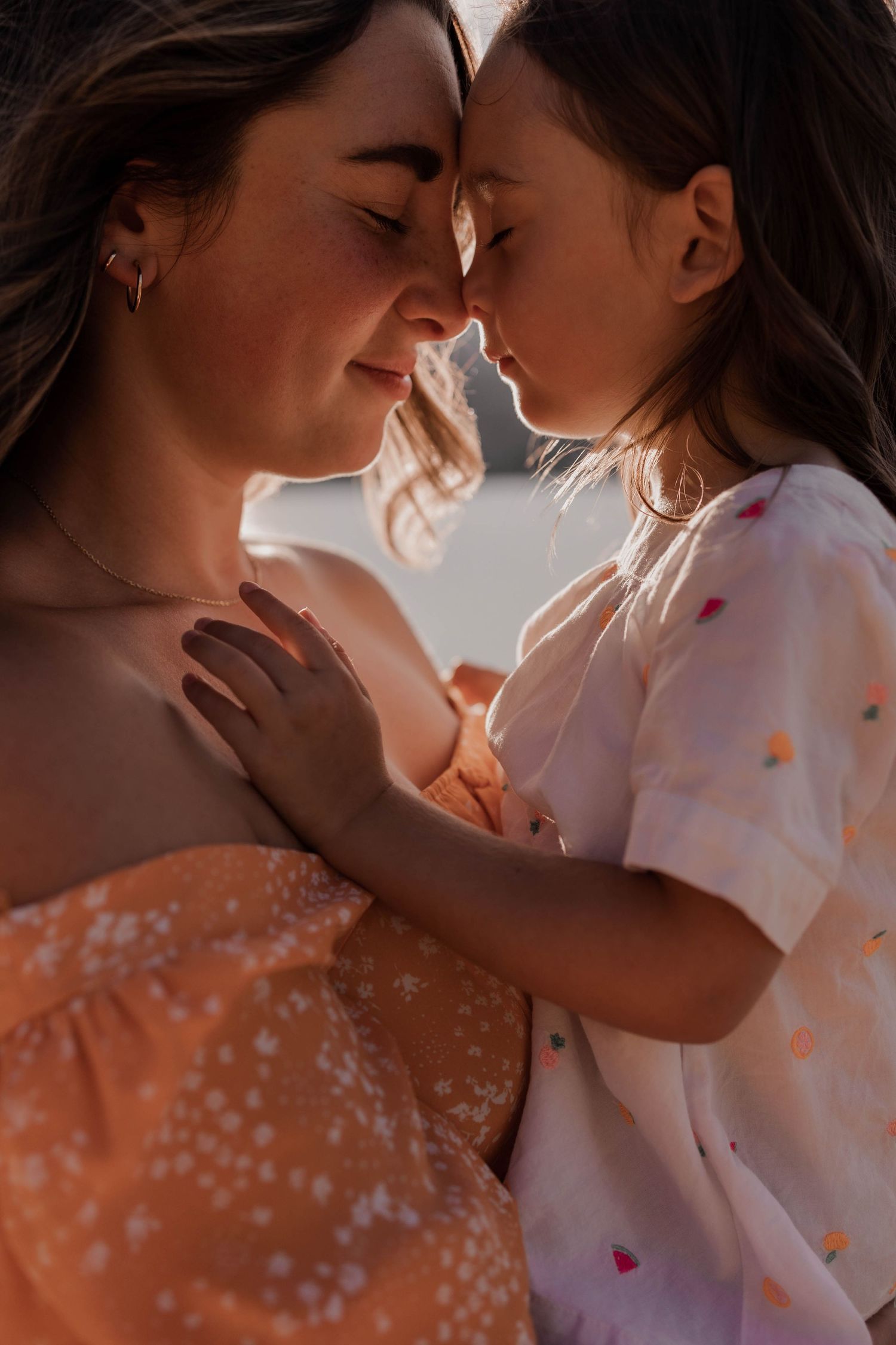 Tender moment between parent and child in warm sunset lighting.