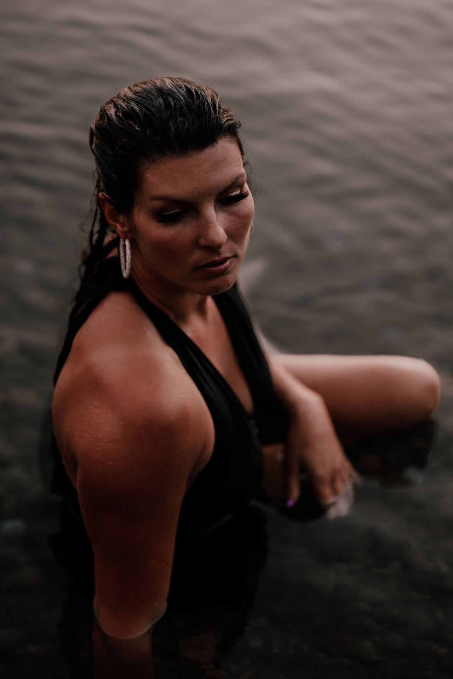 Person in black swimwear enjoying water at dusk with dramatic lighting.