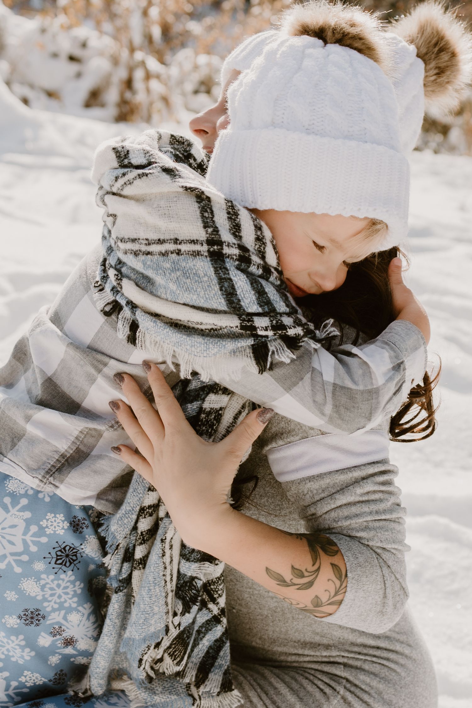 Tender winter moment captured with two people in matching beanies and plaid scarves.