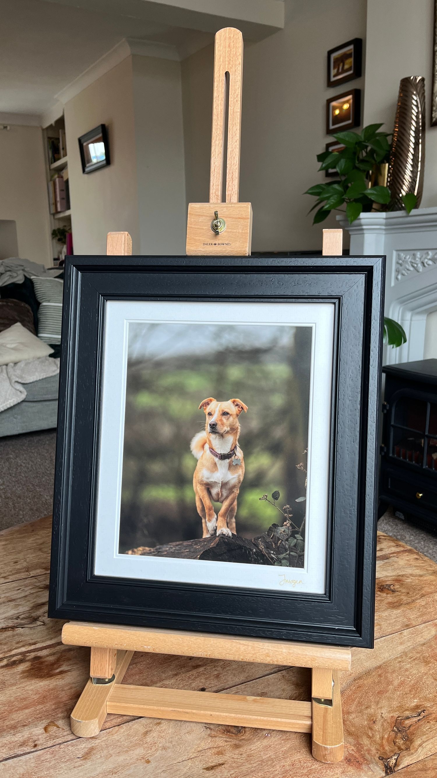 Framed portrait photo of tan dog displayed on wooden easel.