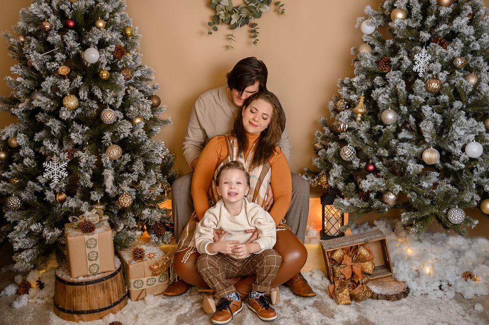 Holiday photoshoot scene with decorated Christmas tree, wooden props, and faux snow on floor.