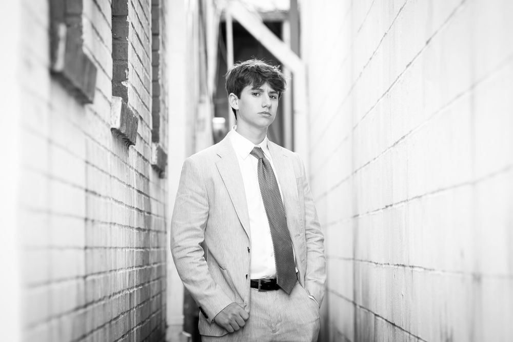 Black and white architectural portrait with person in formal wear standing between white walls.