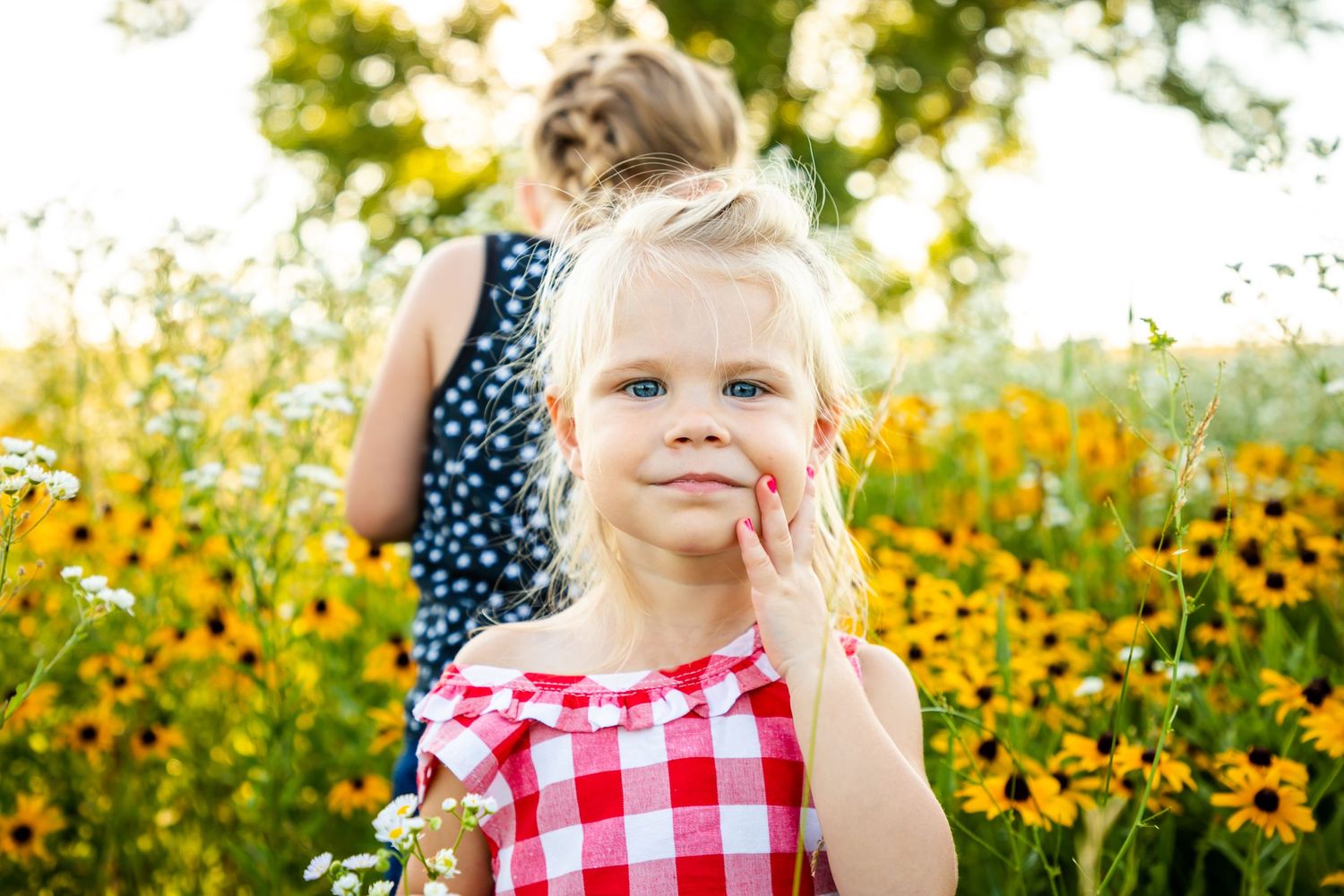 little blonde headed girl outdoors standing in a field of sunflowers