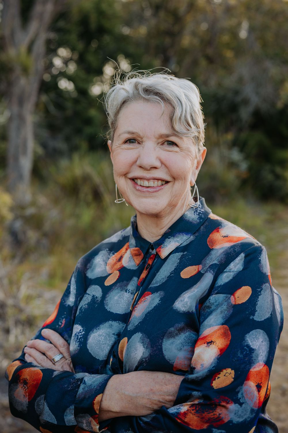 Person wearing a navy blue floral print top posing against a natural outdoor background.