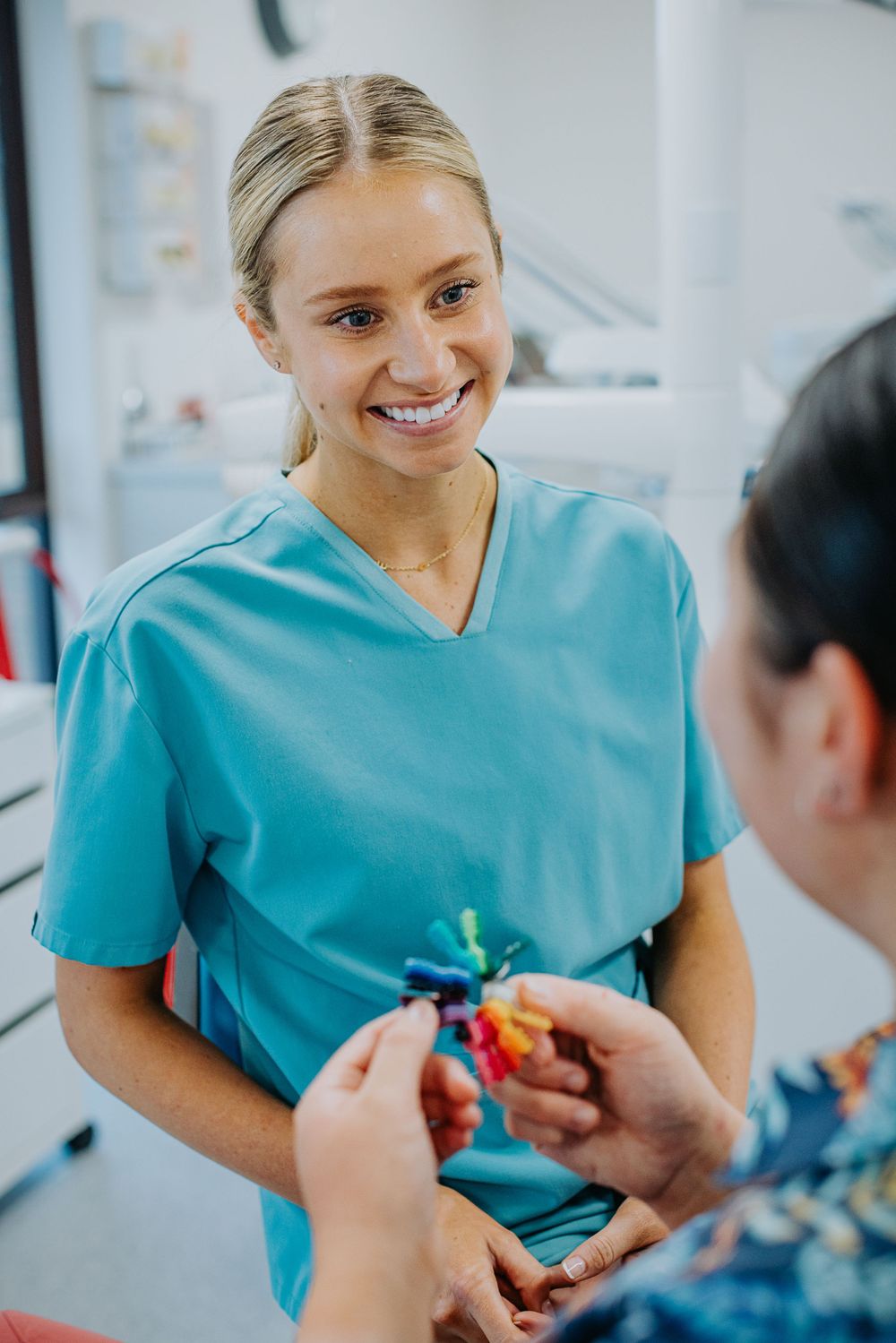 Healthcare worker in turquoise scrubs having conversation in medical setting.