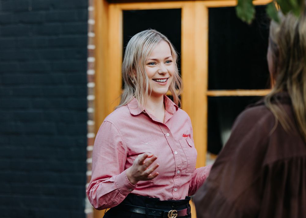 Person in pink shirt engaged in animated conversation outdoors.