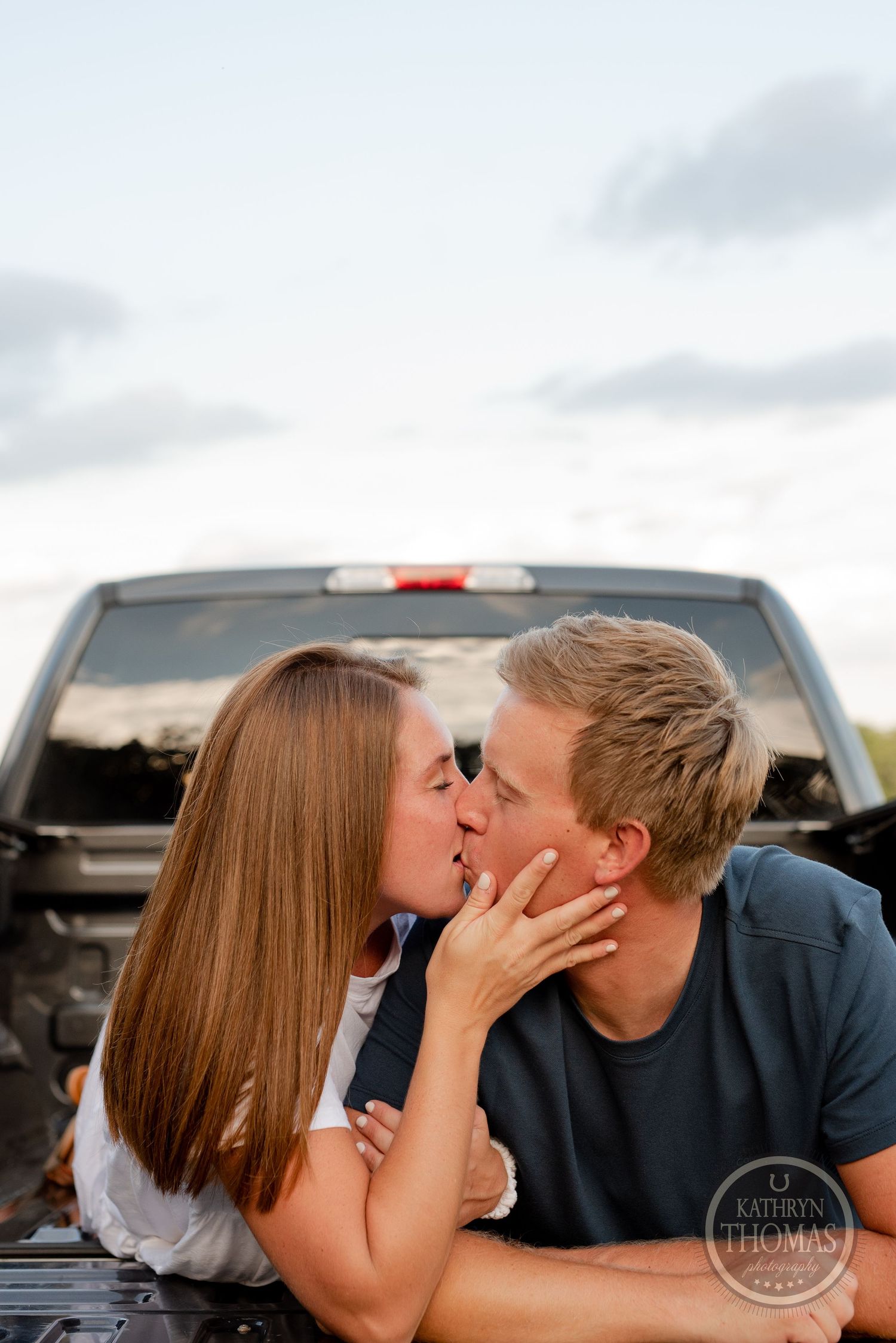 Tender moment shared between couple in white and navy clothing in truck bed.