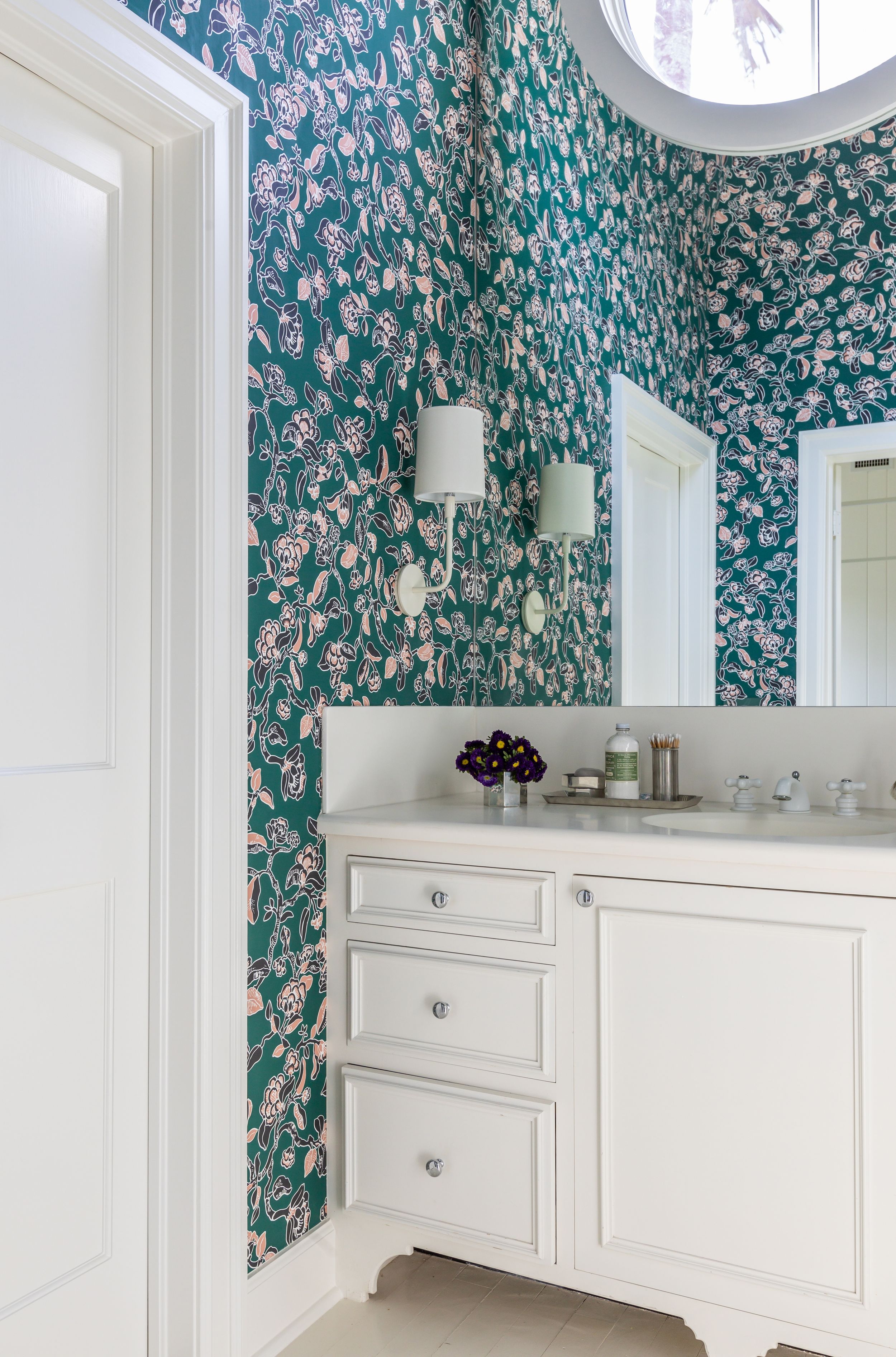 Traditional cottage inspired guest room with dark green wallpaper and white dresser