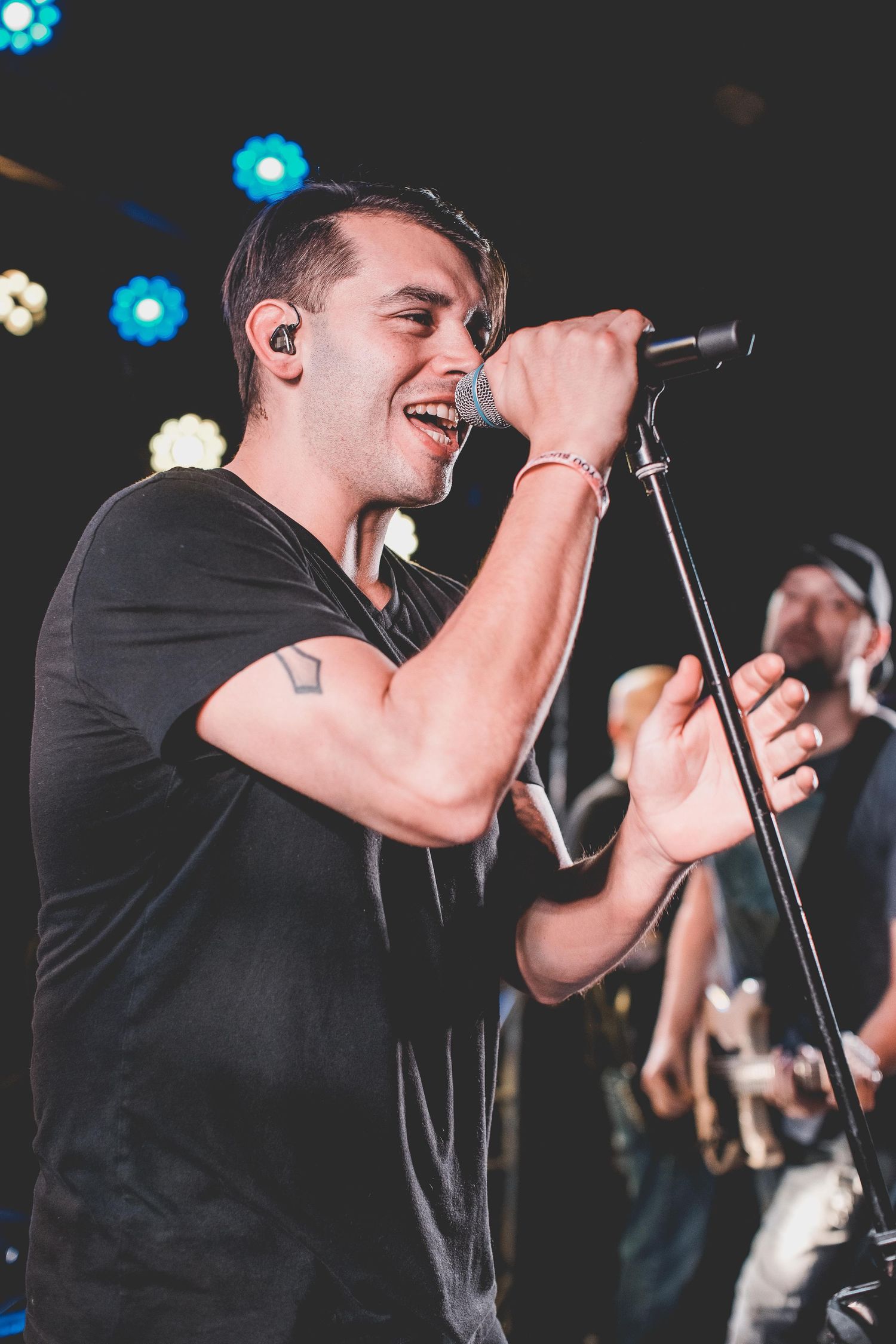 A performer sings passionately into a microphone on stage with blue lighting.