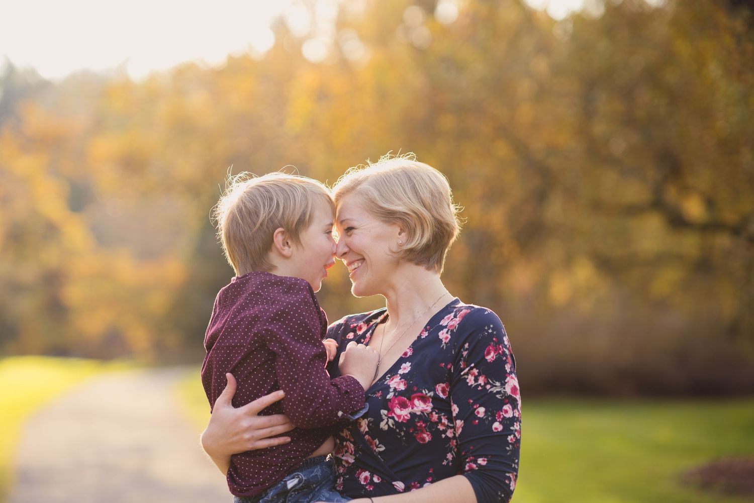 Intimate outdoor portrait session captured during golden hour with fall foliage in the background.