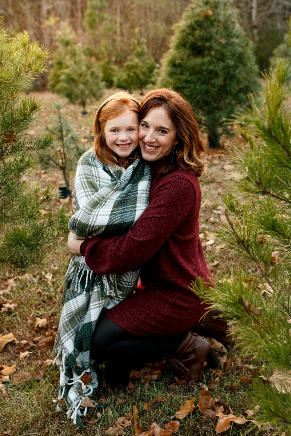 A tender moment shared between parent and child surrounded by evergreen trees.
