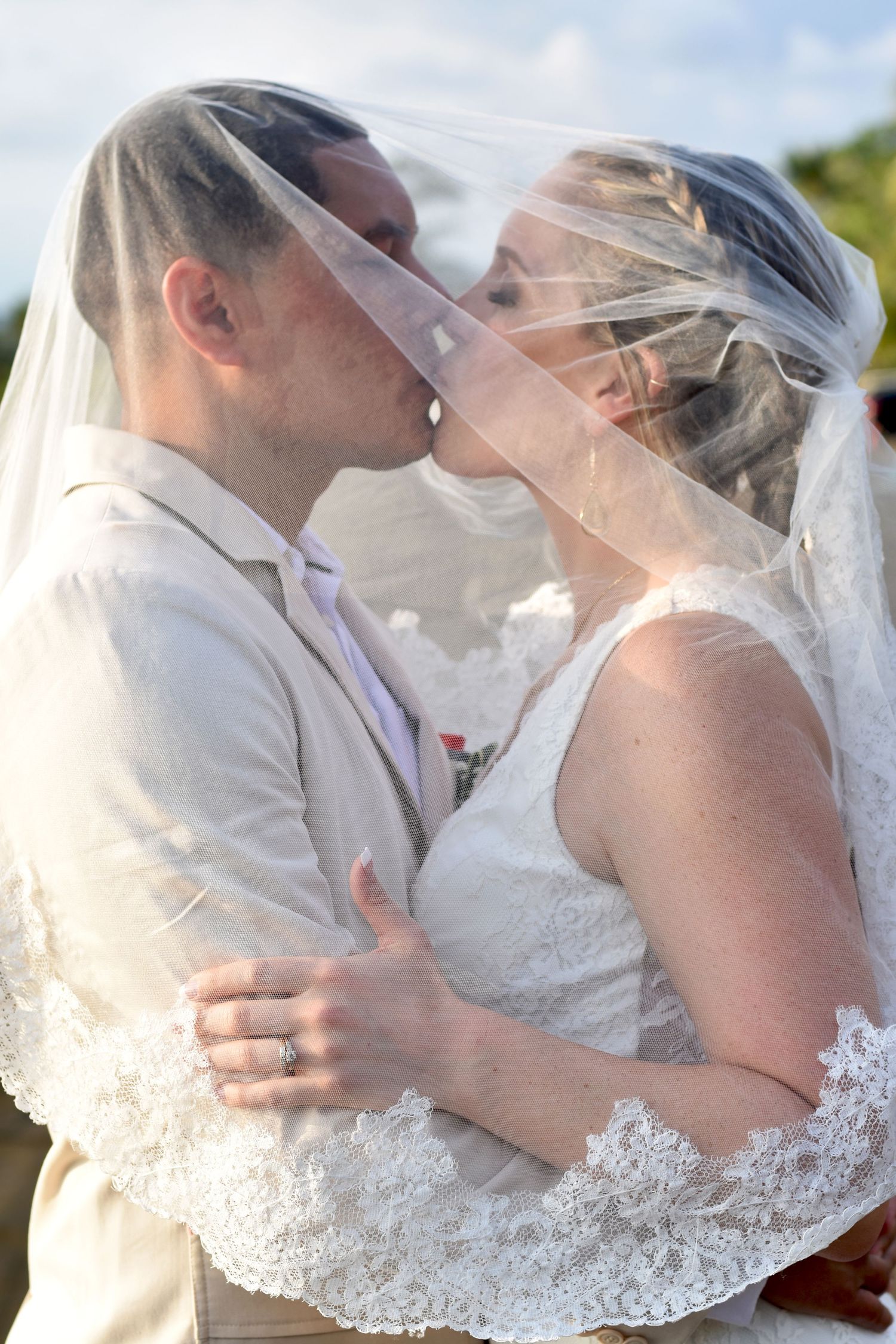 Married couple kissing under a veil