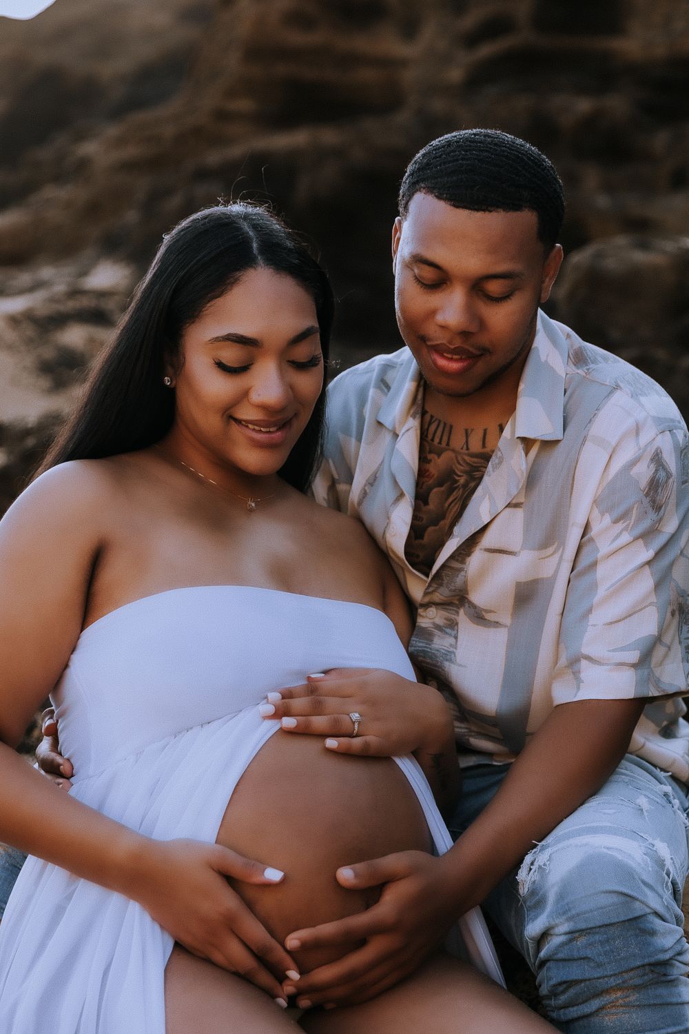 Close-up maternity photos showing tender moments between expectant parents on the beach.