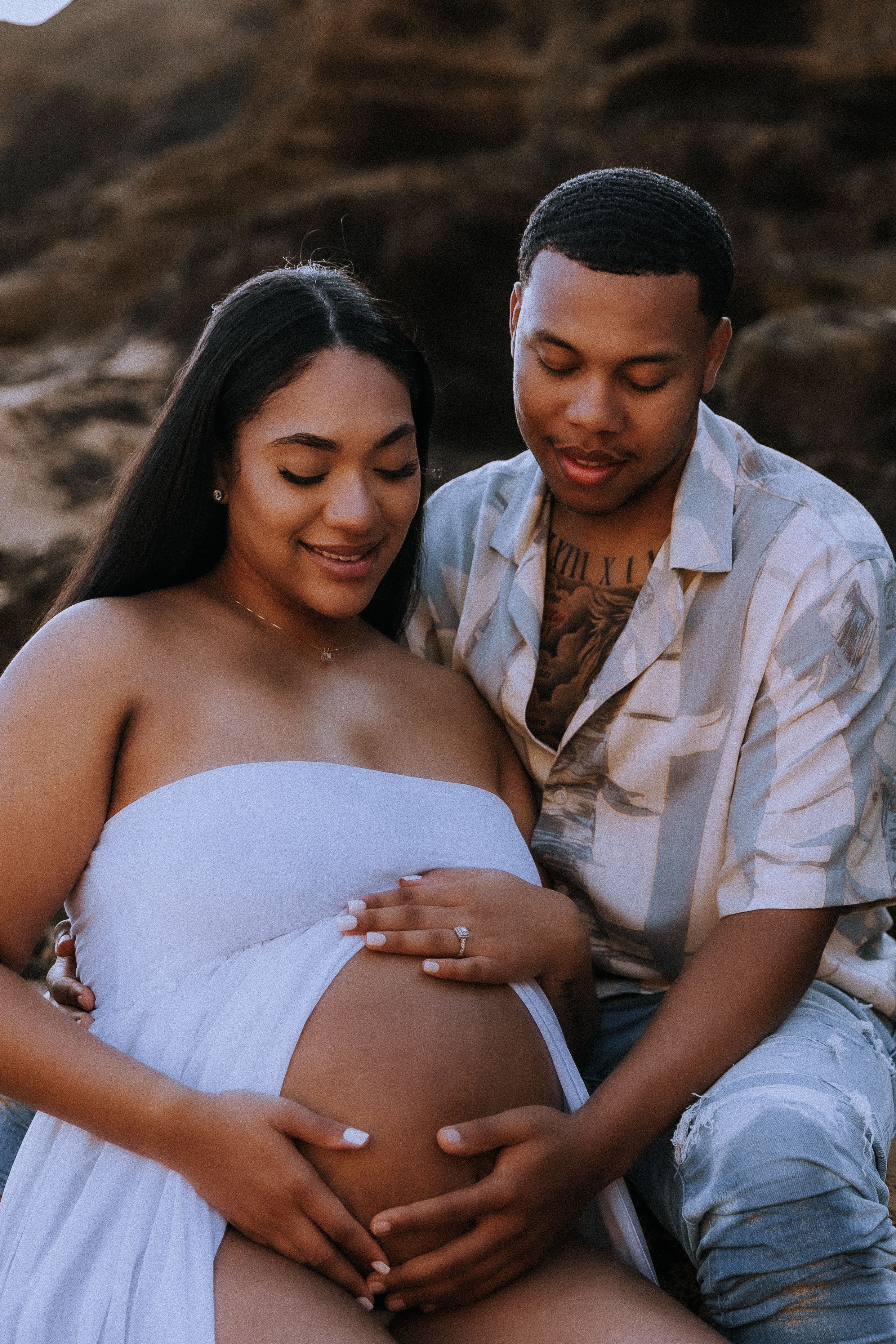 Close-up maternity photos showing tender moments between expectant parents on the beach.