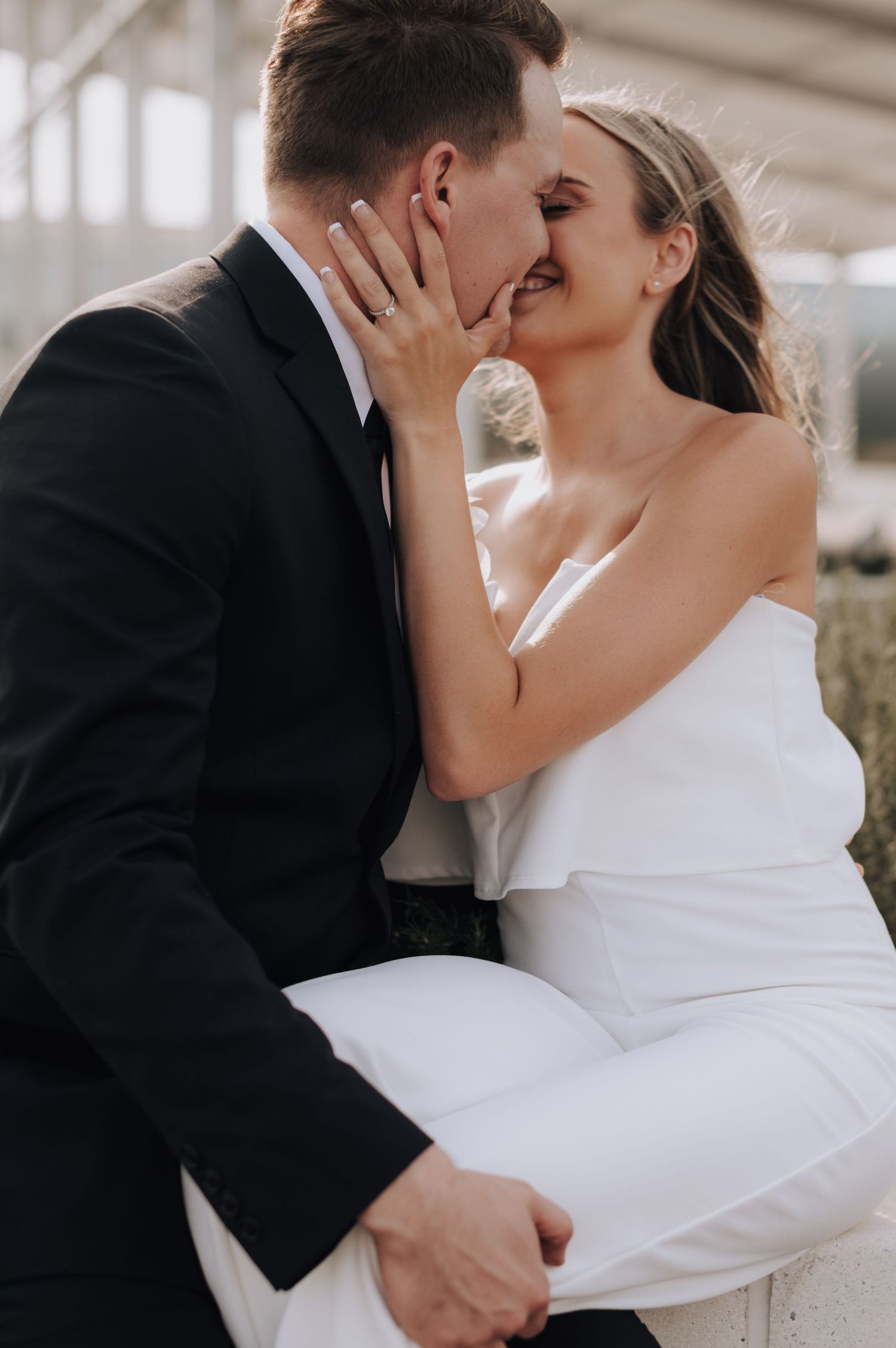 Romantic wedding couple shares an intimate kiss, with the bride in white and groom in classic black suit.