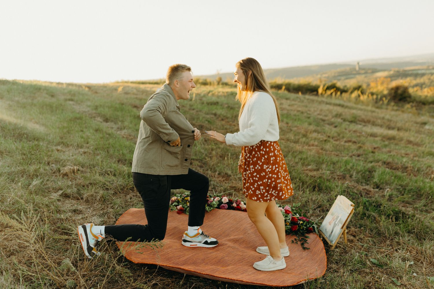 Couple interacting playfully on wooden platform in rural setting at sunset.