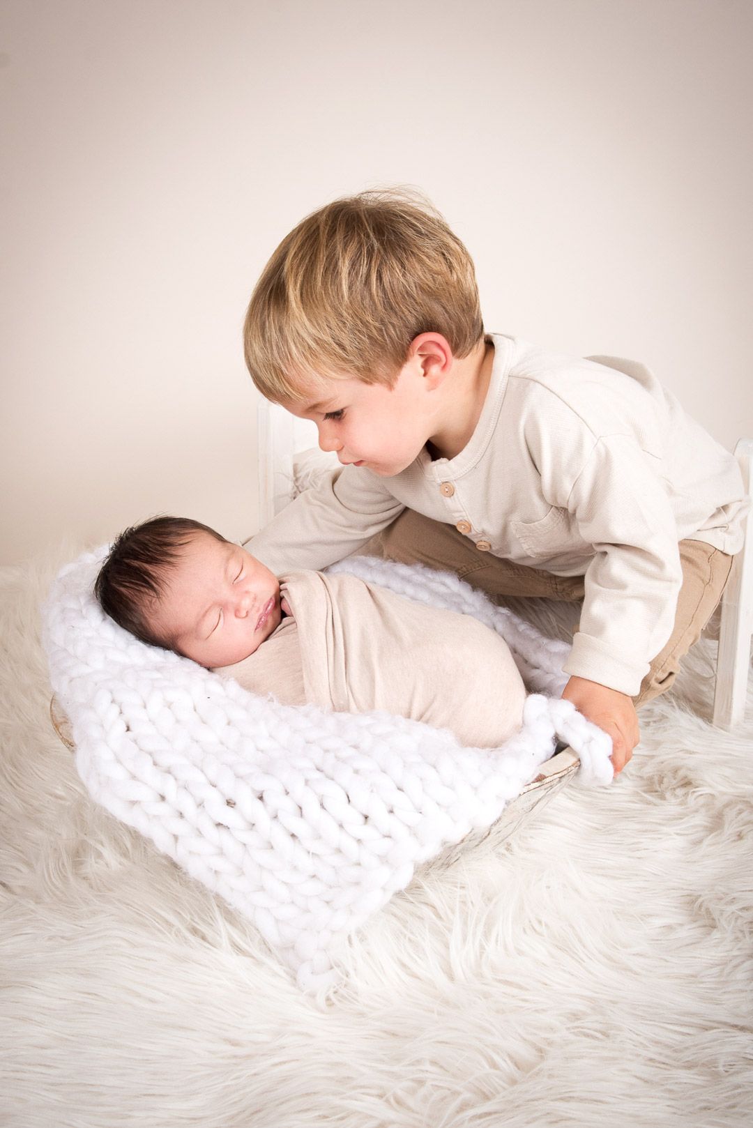 Bruder schaut auf schlafendes Geschwisterbaby