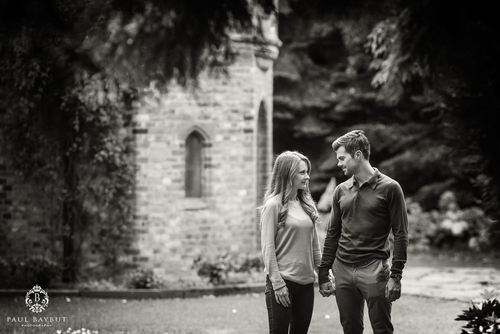 Male and female gaze into each others eyes walking in the park at Walkden Gardens in Sale