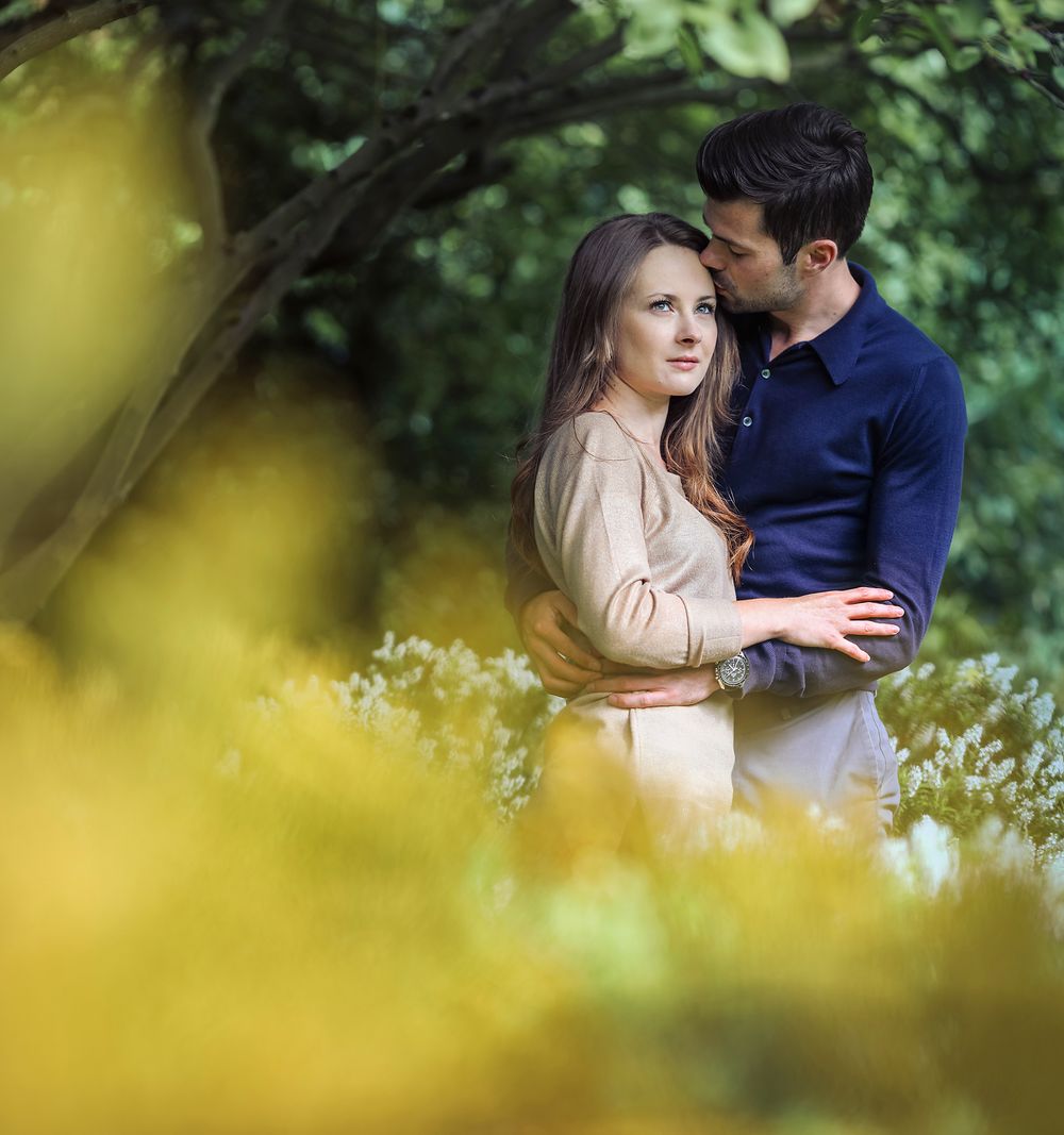 Young couple in love embrace beneath the branches of a tree in Walkden Gardens