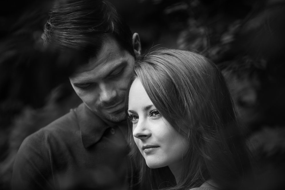 Beautiful female is watched adoringly by her fiancé outside in the park
