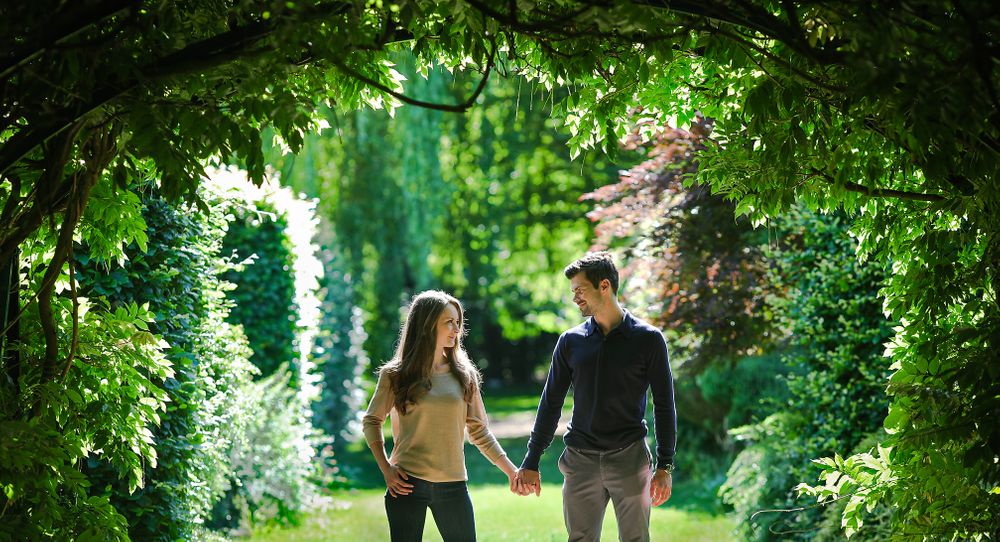 Engagement couple hold hand beneath a hugh canopy of green foliage on a summers day at Walkden Gardens Sale Manchester