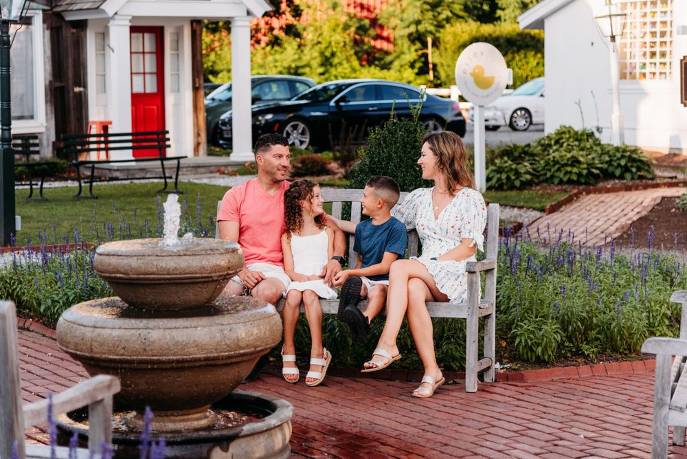 A family relaxes on an outdoor bench near a decorative fountain.