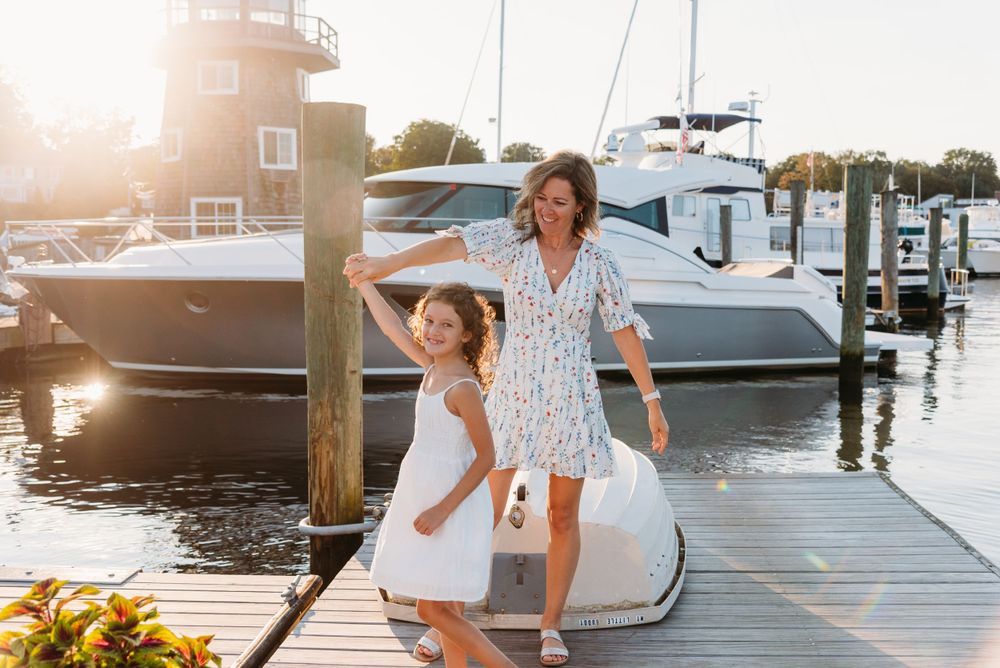A joyful moment captured on a marina dock at sunset with boats in the background.