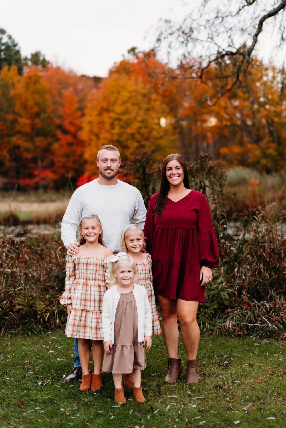 A family portrait captured outdoors against vibrant autumn foliage.