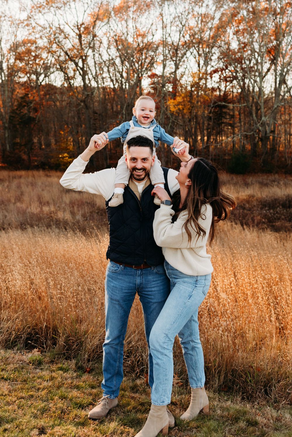 A playful family moment captured in a golden field during fall season.