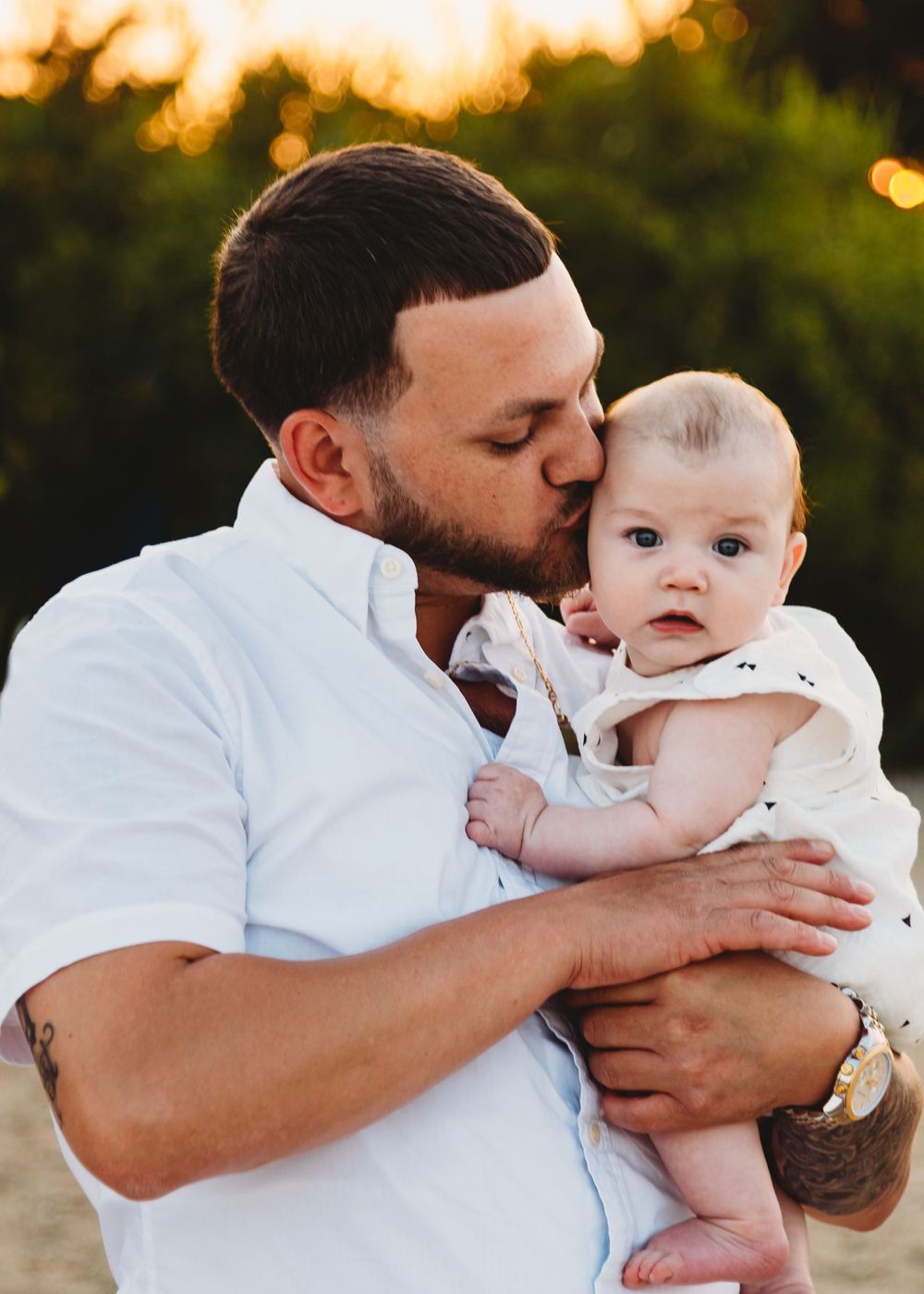 An intimate moment between a parent and baby during golden hour outdoors.