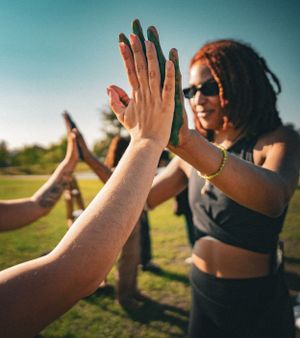 Close-up of hands giving high fives against a vibrant blue sky background.
