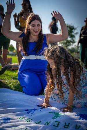 Participants making handprints on a white surface during an outdoor activity.